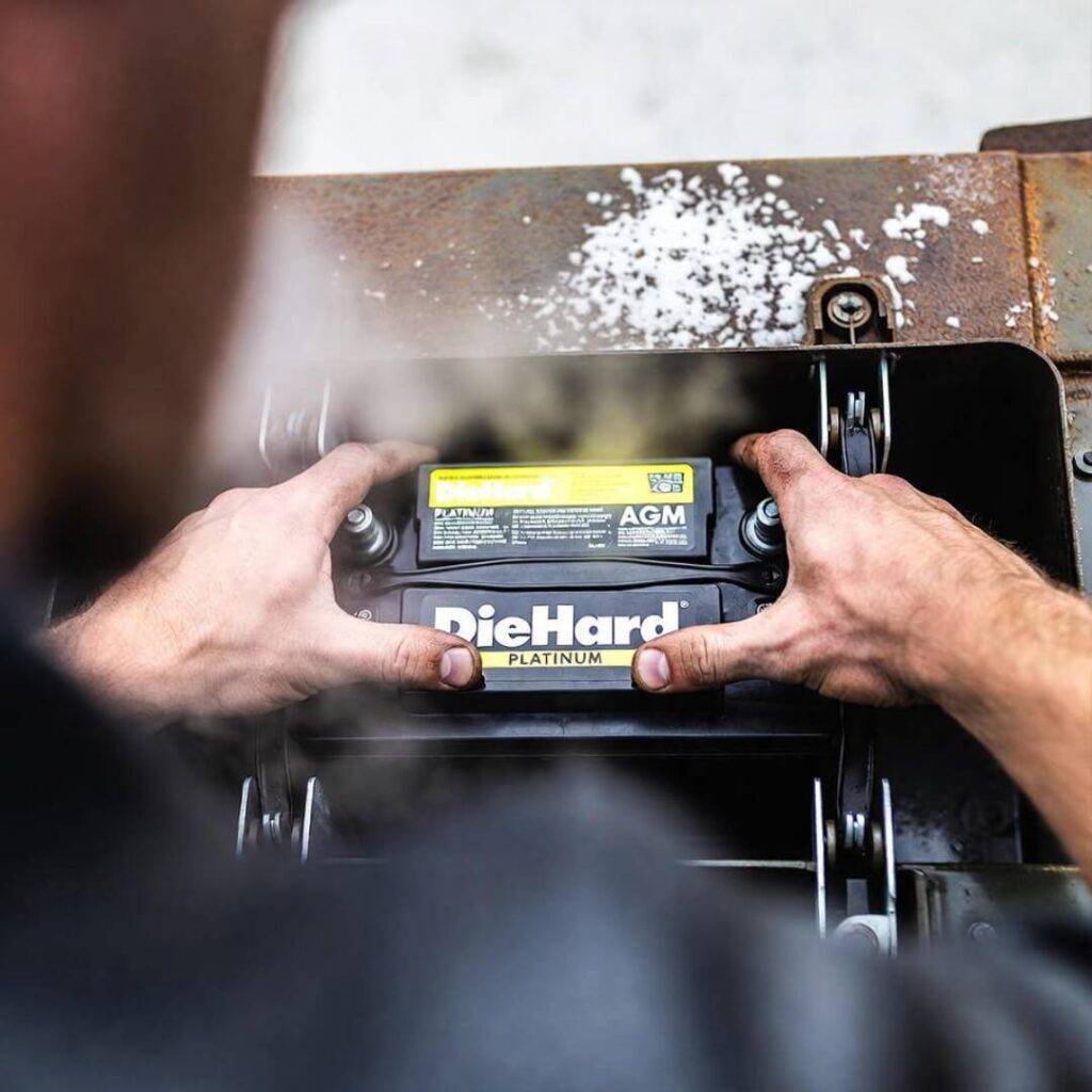 Breath fogs lens as greasy hands fit DieHard battery into salty tray.