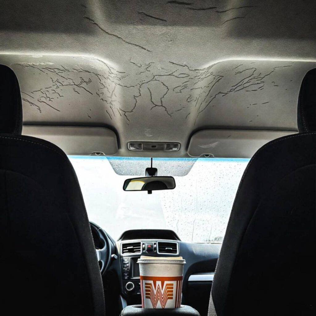 Rain dripping on Whataburger cup under cracked, leaking Subaru headliner.