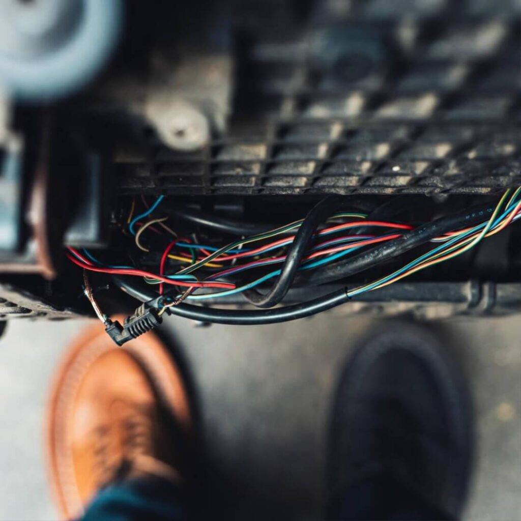 Tangled Type-2 cable under car, chappals in frame.