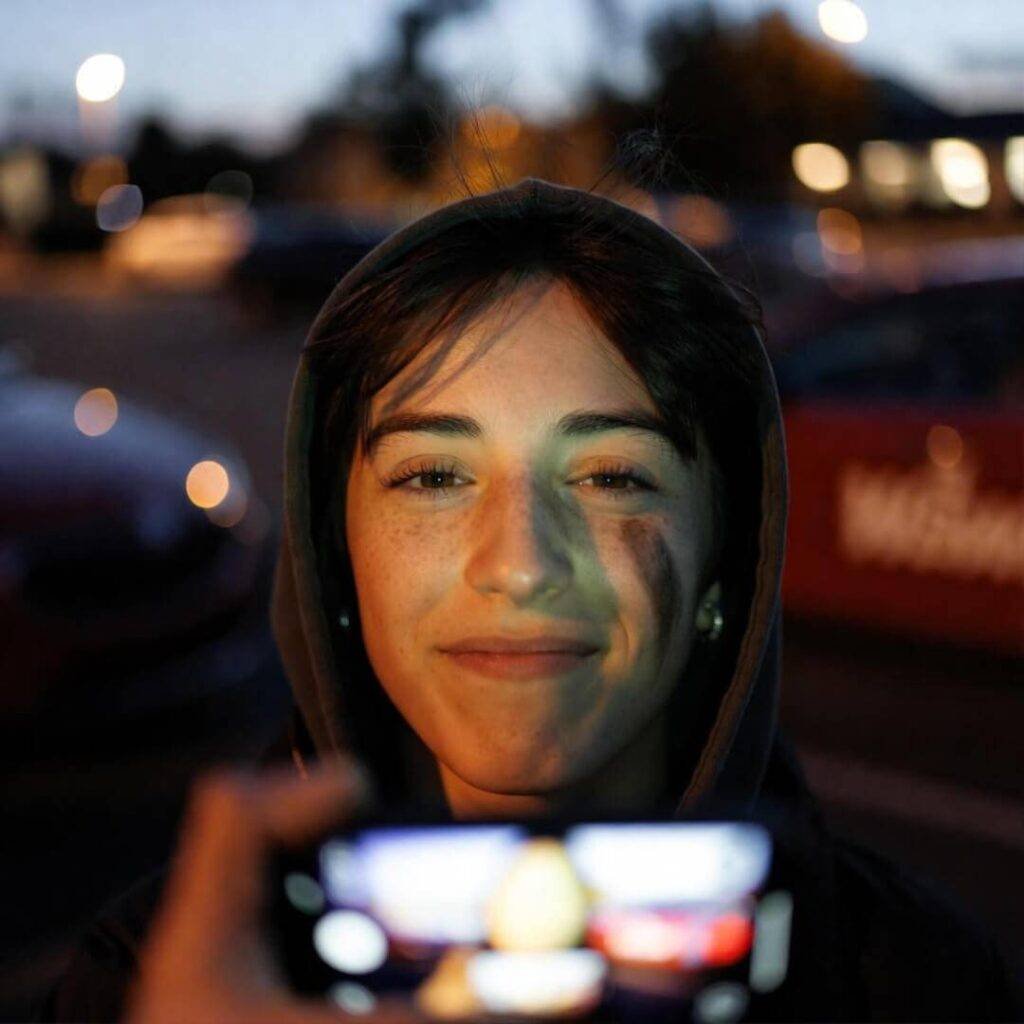 Selfie under hood: squinting, grease-smudged, flashlight-lit in Wawa lot dusk.