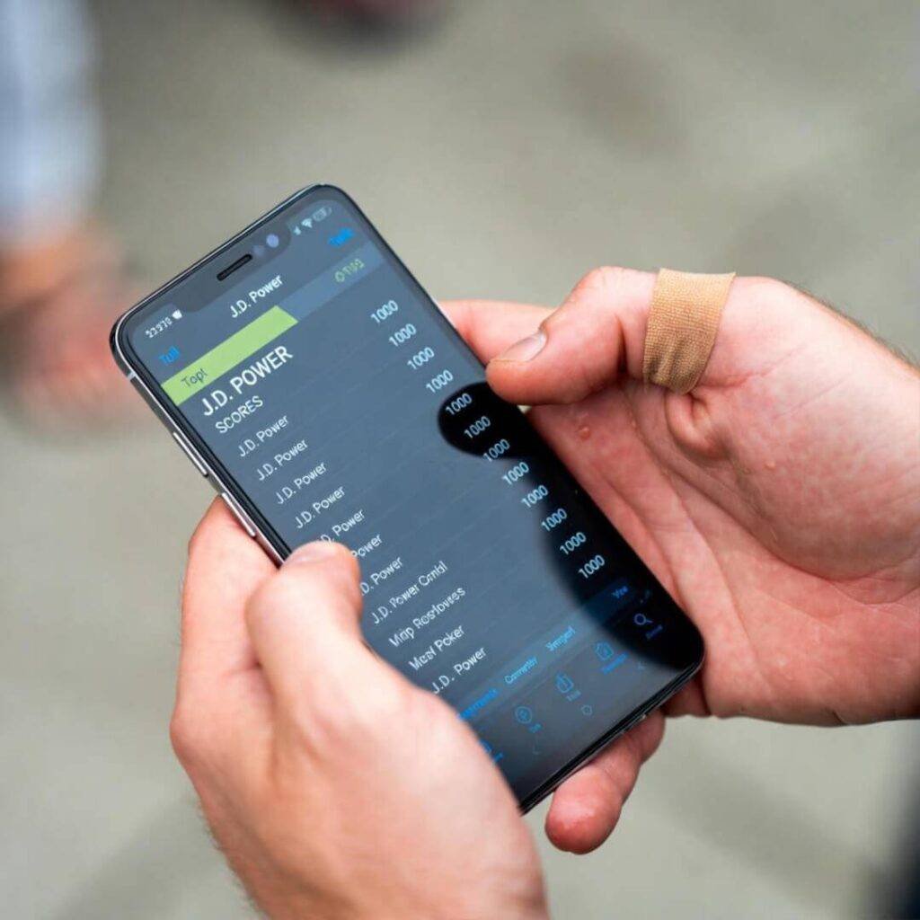 Greasy hands with band-aid holding phone displaying J.D. Power scores.