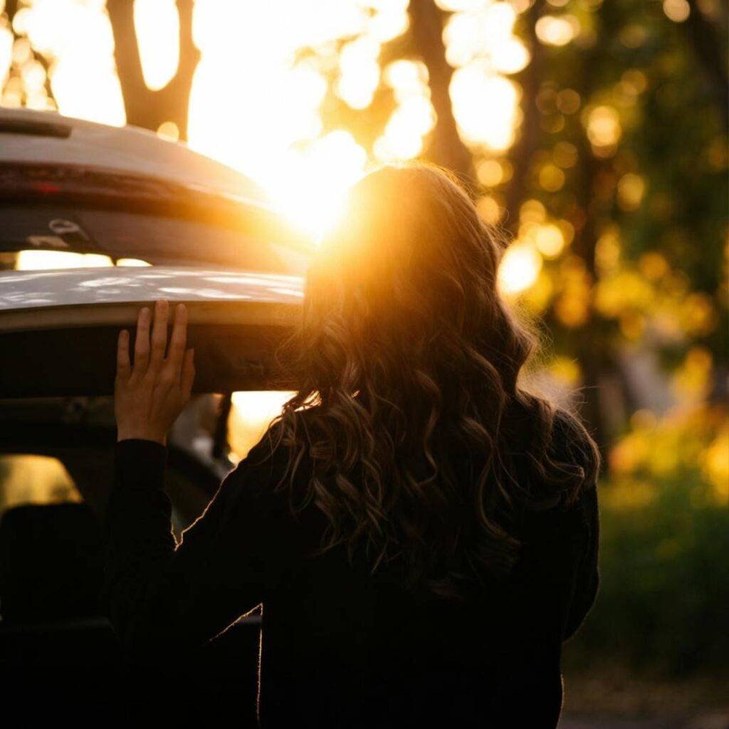 Golden hour glow from open trunk, silhouette against sunset.