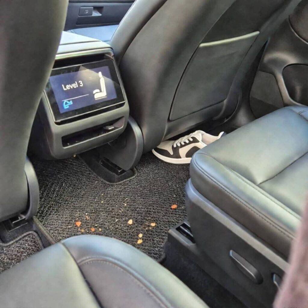 Sneaker on dead pedal, crumbs scattered, massaging seat at Level 3.