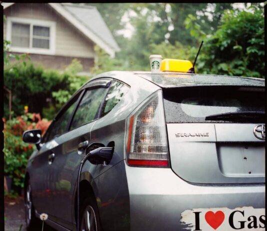 Are Hybrid Cars Worth the Extra Cost? Let’s Break It Down Rainy Seattle driveway: crooked Prius charging, forgotten Starbucks cup, peeling "I ♥ Gas" sticker, lone dandelion.