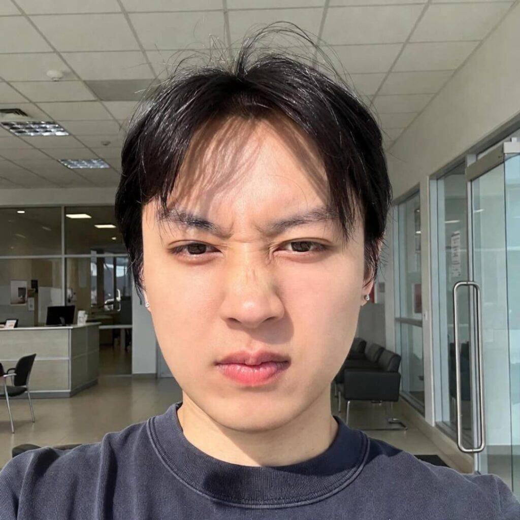 Selfie of young man squinting at invoice, coffee stain on shirt.