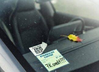 EV Tax Credits Explained: How Much Can You Save? Crooked IRS Form 8936 sticker and "7K credit???" Starbucks receipt on dusty Tesla windshield.