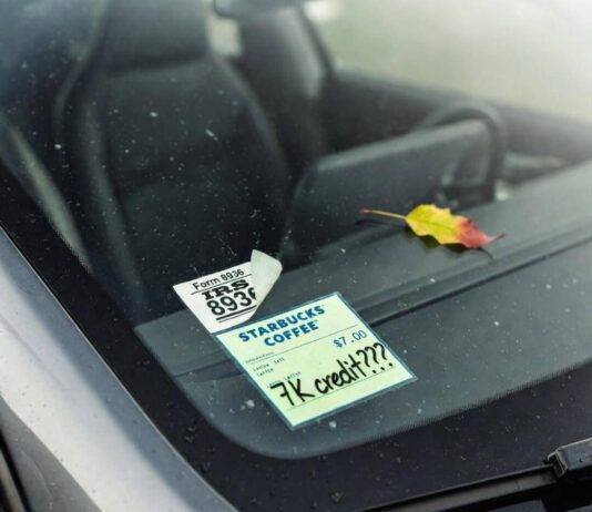 EV Tax Credits Explained: How Much Can You Save? Crooked IRS Form 8936 sticker and "7K credit???" Starbucks receipt on dusty Tesla windshield.