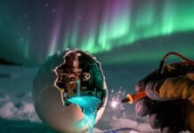 Best Car Batteries for Cold Weather: Winter-Proof Your Ride Cracked frozen battery spills glowing blue electrolyte on snowy Minnesota plate under aurora.