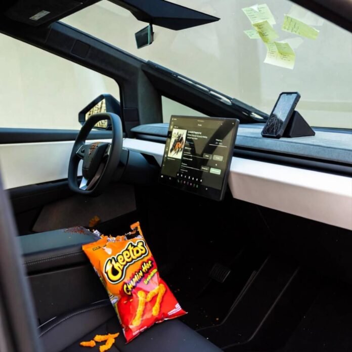 Messy Cybertruck interior: spilled Flamin’ Hot Cheetos, cracked phone streaming lo-fi, sticky notes.