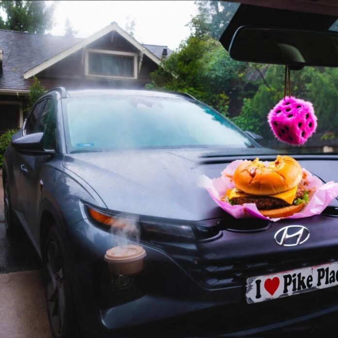 Rainy Seattle driveway: beat-up Hyundai Tucson with coffee steam, neon pink dice, greasy burger.