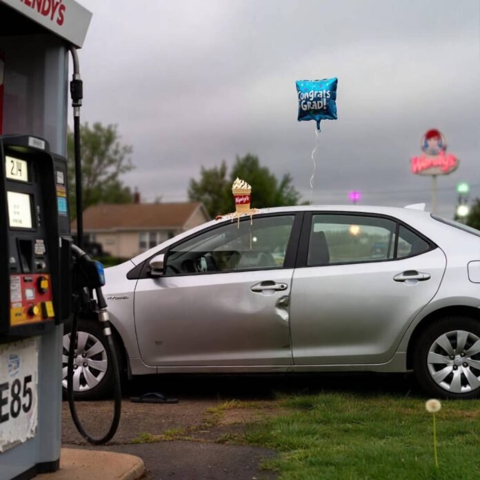 Dented Corolla with melting Frosty, deflated balloon, flip-flop under tire at E85 pump.